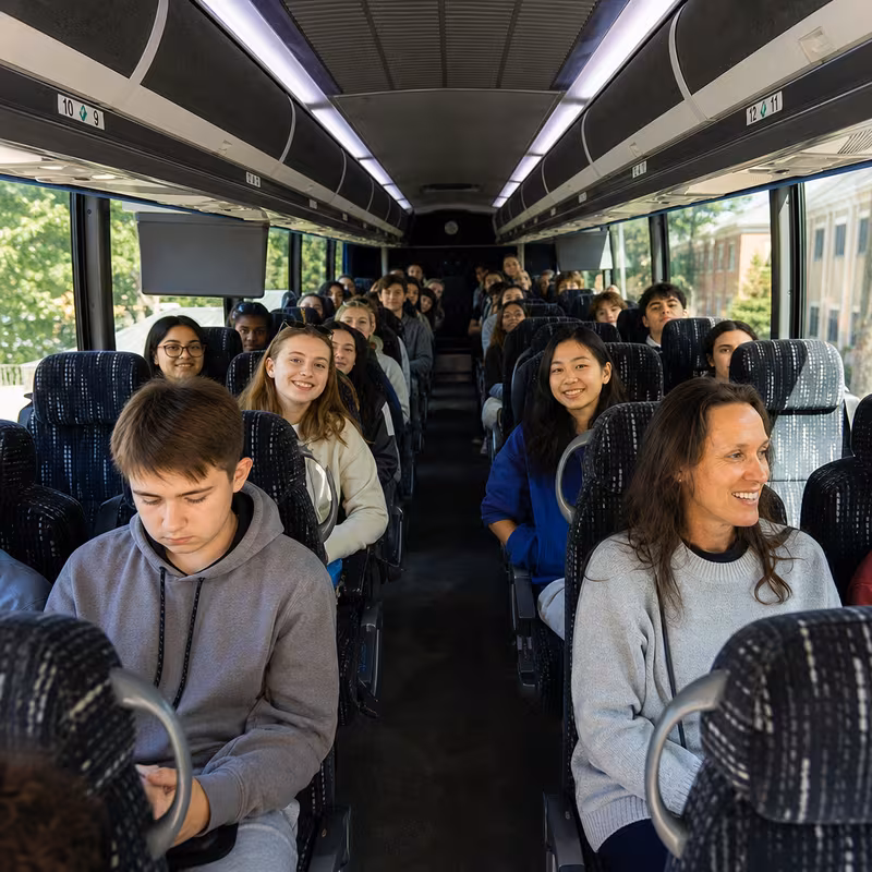 Group boarding a white charter bus for School Transportation transportation in Atlanta